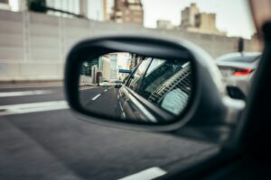 Reflection of city buildings in a car's side mirror.